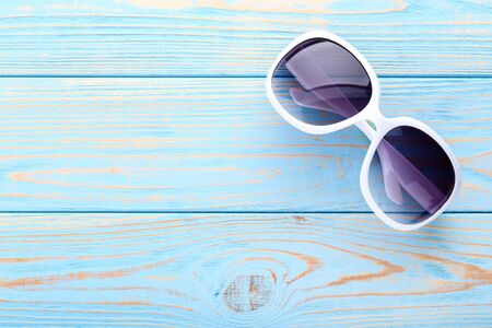 Modern sunglasses on blue wooden tableの写真素材