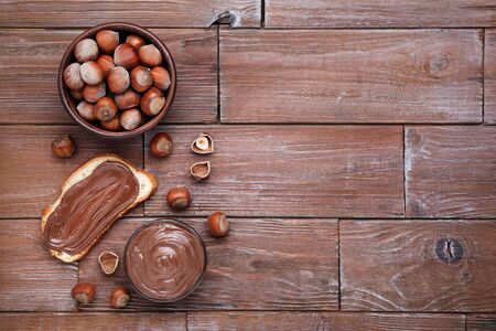Bread with melted chocolate and hazelnuts on brown wooden tableの写真素材