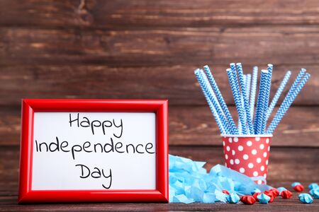 Text Happy Independence Day with paper stars and straws in cup on wooden tableの写真素材
