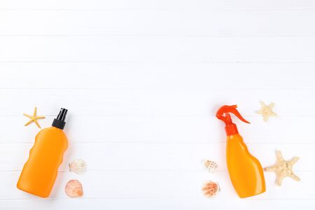 Sunscreen bottles with seashells on white wooden tableの写真素材