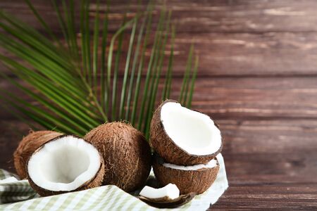 Ripe coconuts with palm leaves on wooden table