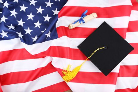 Graduation cap with diploma on American flag backgroundの写真素材