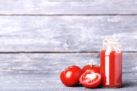 Tomato juice in glass bottle on grey wooden tableの写真素材