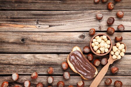 Bread with melted chocolate and hazelnuts on wooden tableの写真素材
