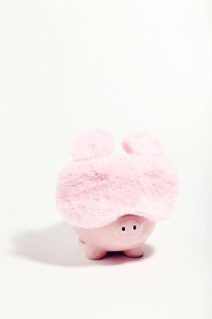 Piggybank with sleeping mask on white background. Minimalism conceptの写真素材