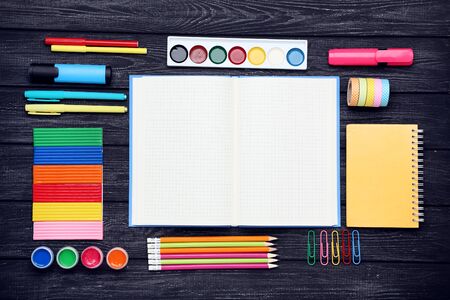 School supplies with blank sheet of paper on black wooden tableの写真素材