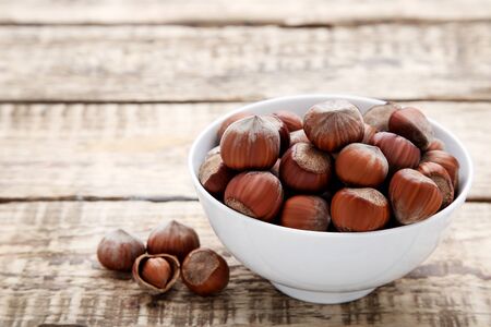 Hazelnuts in bowl on wooden tableの写真素材
