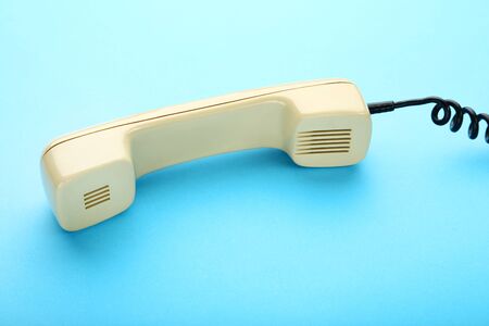 Beige telephone handset on blue background