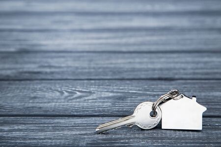 Silver key with house symbol on black wooden tableの写真素材