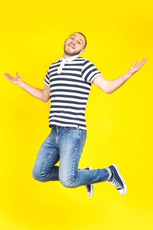 Jumping young man on yellow backgroundの写真素材