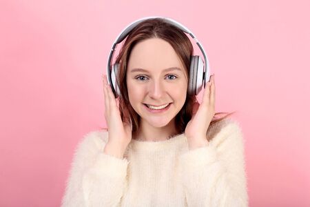 Young girl with headphones on pink background