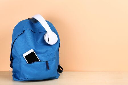 School backpack with headphones and smartphone on beige backgroundの写真素材