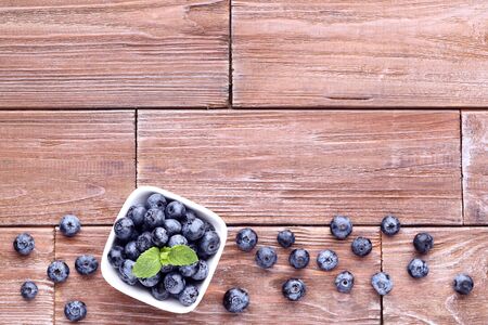 Ripe blueberries with green leafs on wooden tableの写真素材