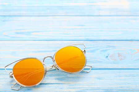 Modern sunglasses on blue wooden tableの写真素材