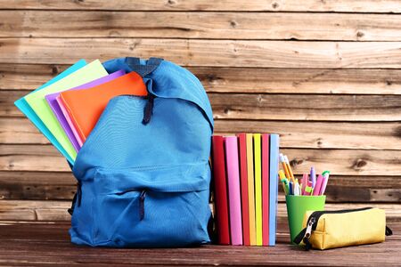 Backpack with school supplies on brown wooden tableの写真素材