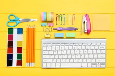 School supplies with keyboard on yellow wooden tableの写真素材