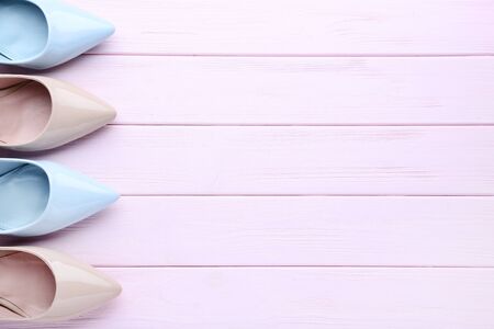 Different high heel shoes on pink wooden table