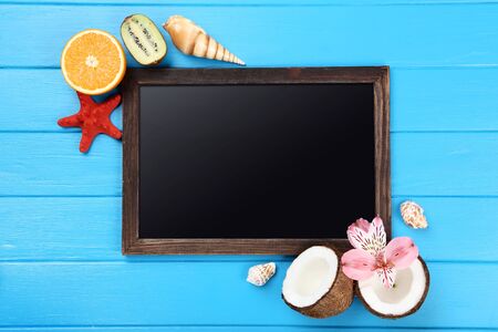 Wooden blank frame with seashells and fruits on blue tableの写真素材