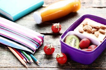 School lunch box with sandwich and fruits on wooden tableの写真素材