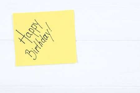 Paper with text Happy Birthday on white wooden table