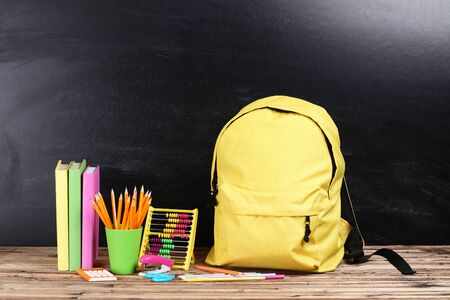 Backpack with school supplies on black background