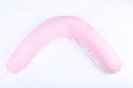 Pink body pillow on white bedの写真素材
