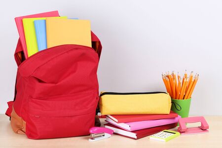 Backpack with school supplies on grey background