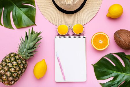 Fashion clothing with green leafs, different fruits and blank notepad on pink background