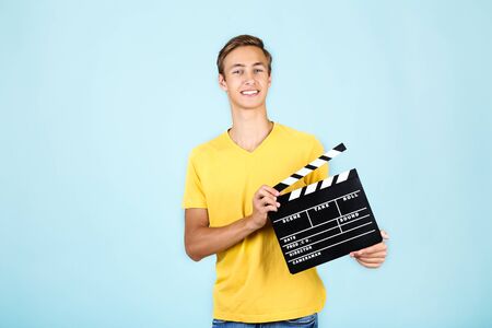 Young man with clapper board on blue backgroundの写真素材