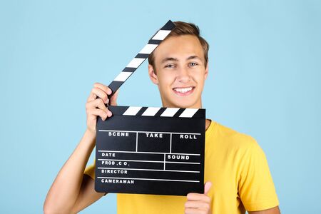 Young man with clapper board on blue background