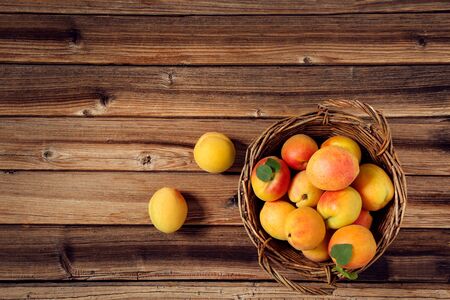 Sweet apricots in basket on brown wooden tableの写真素材