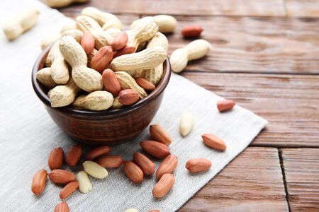 Peanuts in bowl on brown wooden table
