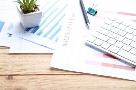 Financial papers with keyboard and green plant on wooden tableの写真素材