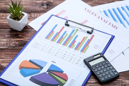 Financial papers with graph, charts and calculator on wooden table