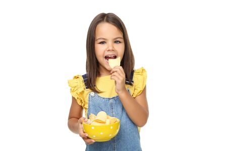 Beautiful little girl with potato chips in bowl on white backgroundの写真素材