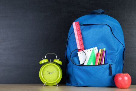 School supplies with blue backpack on blackboard backgroundの写真素材
