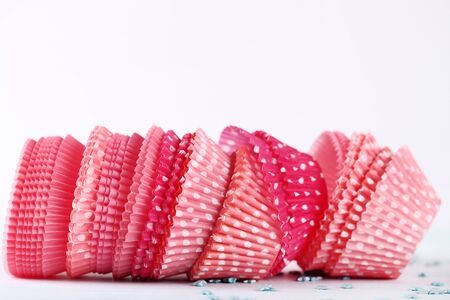 Pink cupcake cases on white wooden tableの写真素材
