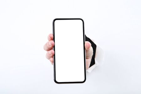 Hand holding smartphone from white torn paperの写真素材