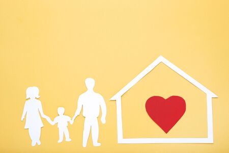 Family and house figures with red heart on yellow backgroundの写真素材