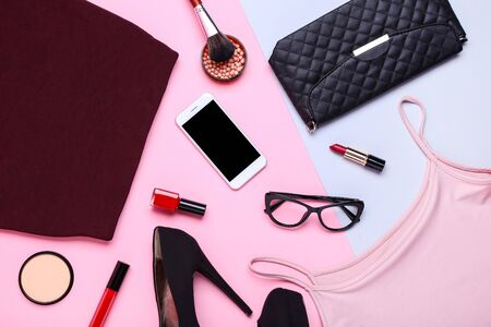 Modern women's clothes with makeup cosmetics and accessories on colorful backgroundの写真素材