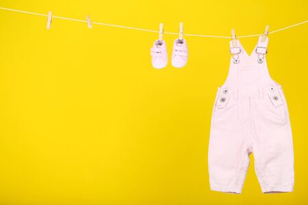 Baby clothes hanging on yellow backgroundの写真素材