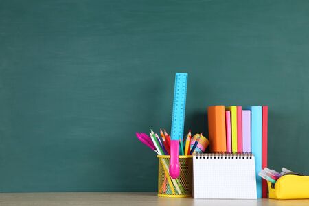School supplies with black sheet of paper on green background
