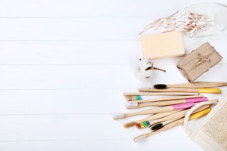 Bamboo toothbrushes with soap, washcloth and cotton sticks on white wooden table