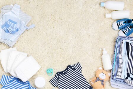 Baby clothes with toys and diapers on carpetの写真素材