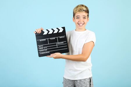 Young boy with clapper board on blue backgroundの写真素材