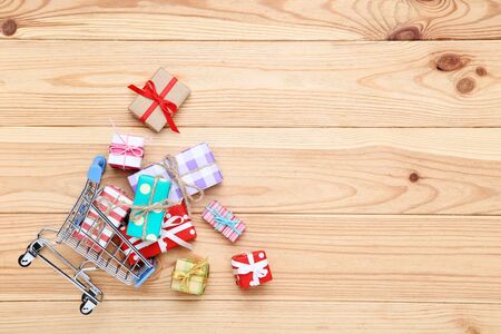 Small shopping cart with gift boxes on brown wooden tableの写真素材