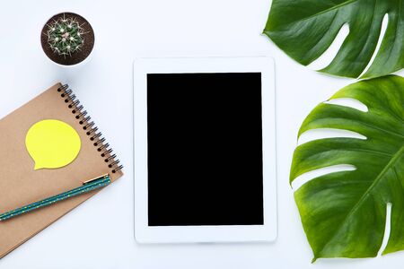 Tablet computer with notepad, cactus and monstera leafs on white backgroundの写真素材