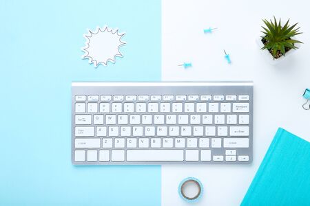 Computer keyboard with office supplies and green plant on colorful backgroundの写真素材