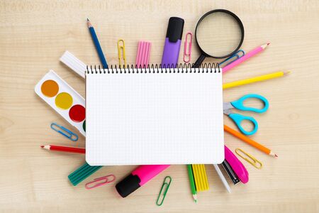 School supplies with blank sheet of paper on brown wooden table