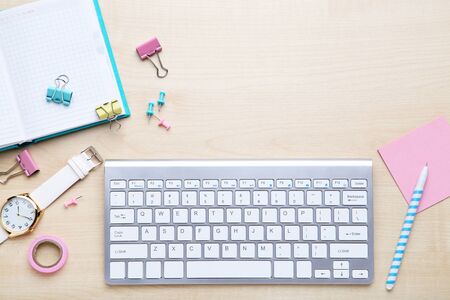 Computer keyboard with notepad, pen and wrist watch on wooden tableの写真素材
